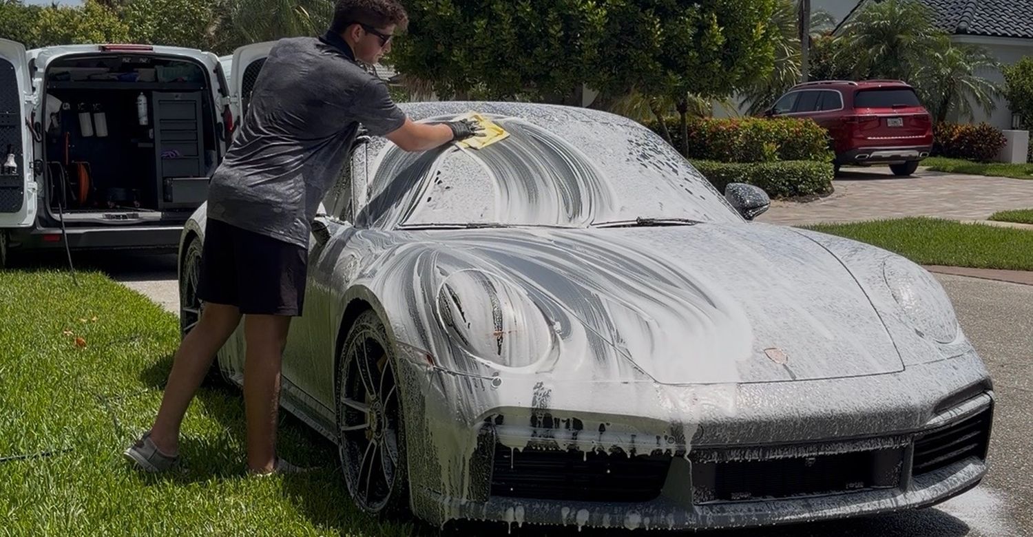Dany foam-washing a Porsche 911 on-site, service van open with equipment